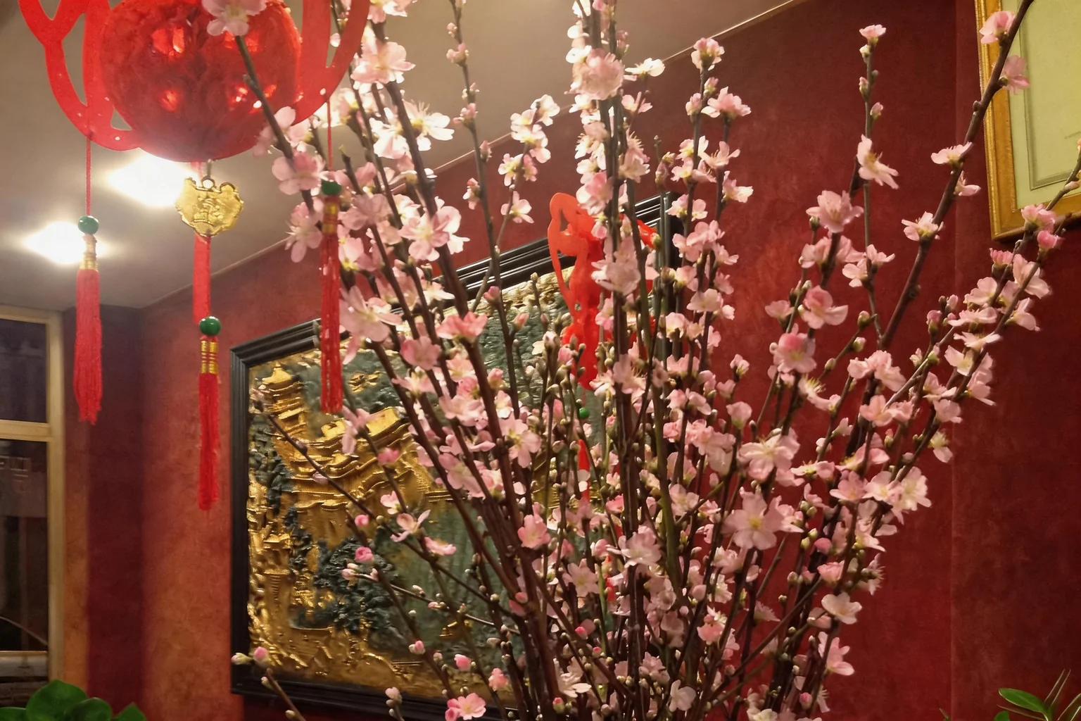Dining room: flowering branches in a vase, red lantern and gilded panel
