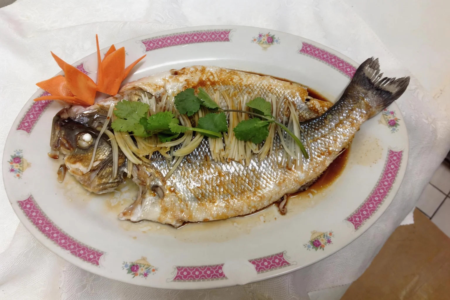 Whole fish on an oval dish with a pink border